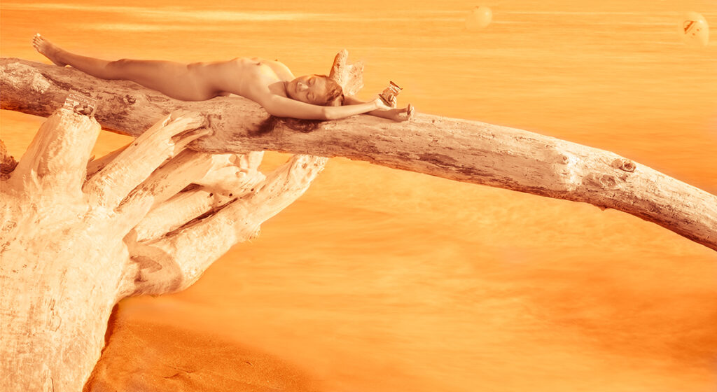 naked woman stretches across treetrunk on seashore